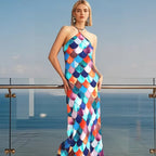 Woman wearing a colorful halter neck dress standing on a balcony with ocean view