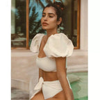Woman wearing a white bikini with puffed sleeves in an outdoor setting