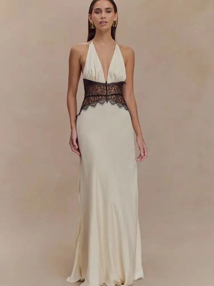Woman wearing a white evening gown with black lace details on a beige background
