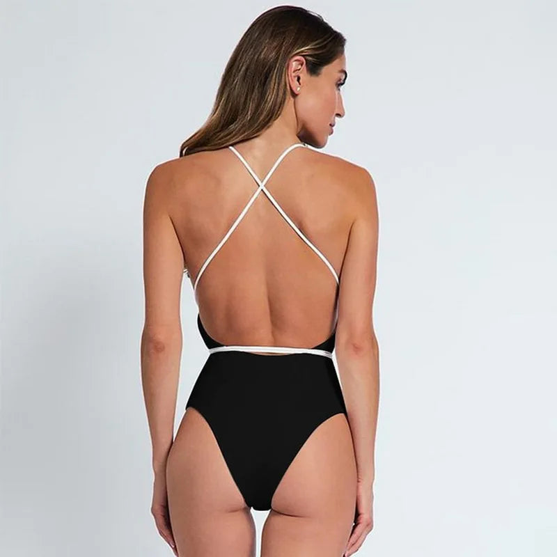 Woman wearing a black swimsuit with white straps on a light gray background