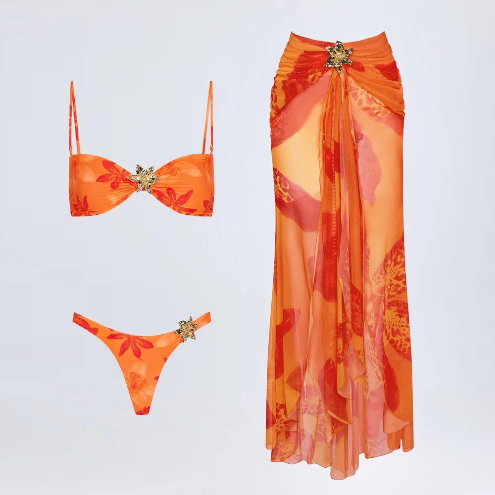 Orange floral bikini set with a matching long skirt on a light gray background