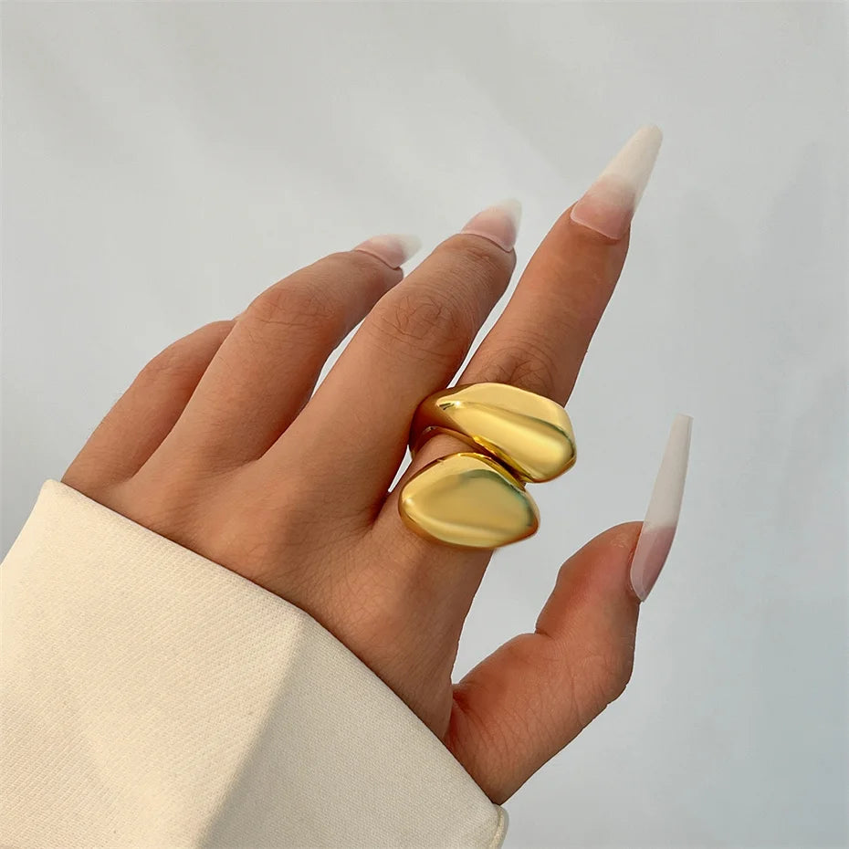 Hand wearing two gold rings with a plain background