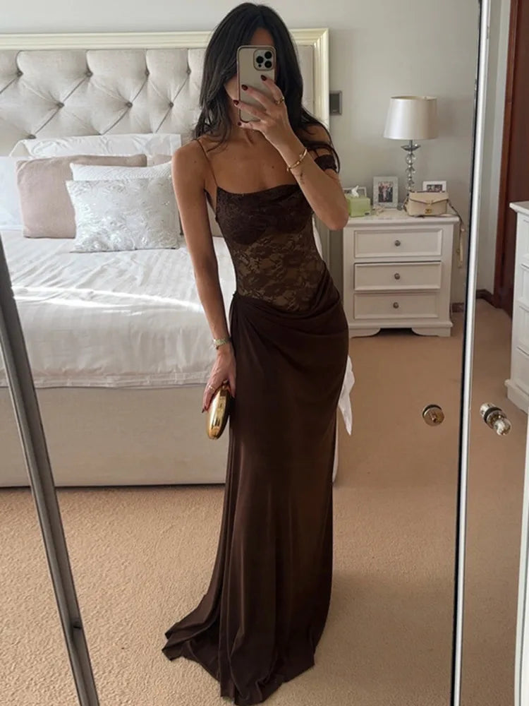 Woman in a brown evening gown taking a mirror selfie in a bedroom.