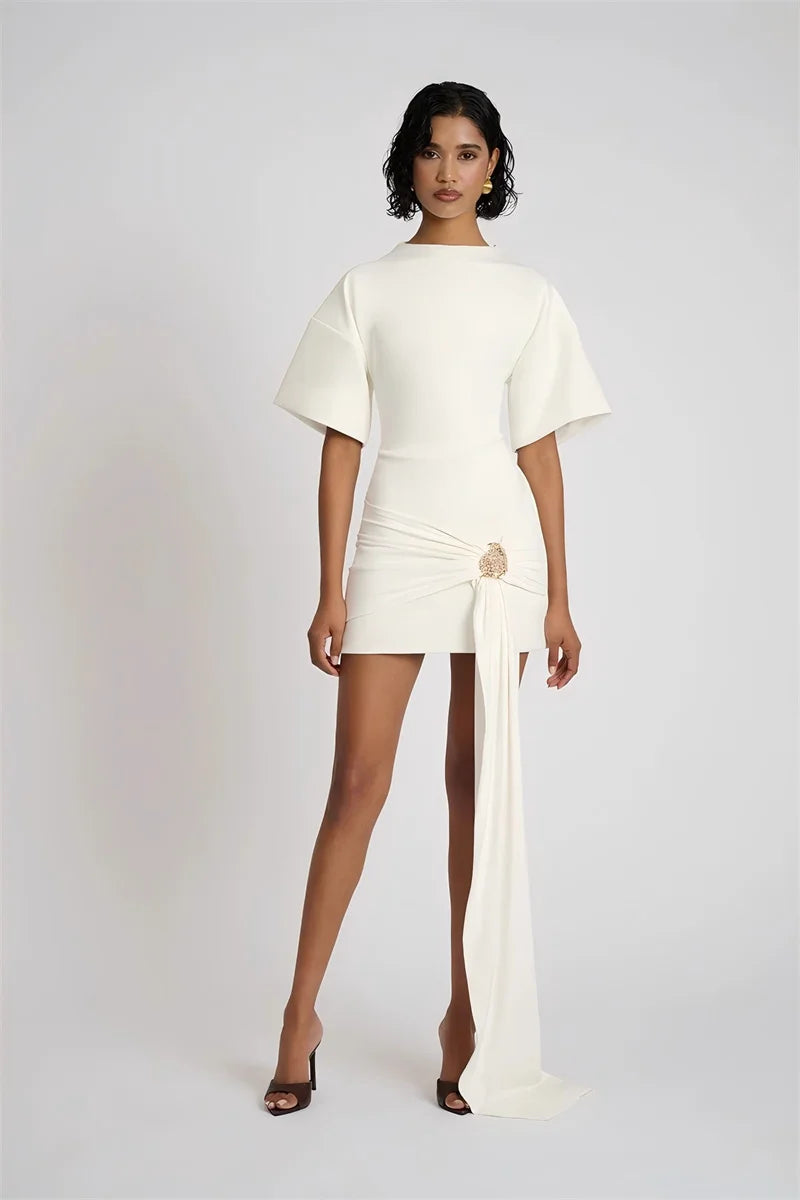 Woman wearing a white outfit with a flowing skirt on a plain background