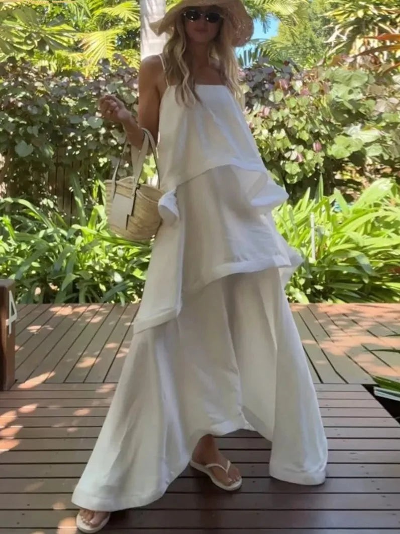 Woman in a white dress standing outdoors with greenery in the background
