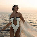 Woman in a stylish swimsuit with a floral design on a boat at sunset.