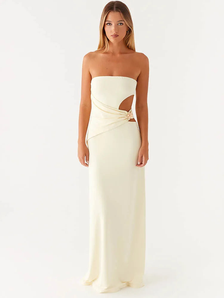 Woman wearing a strapless, long, off-white dress with cut-out design on a white background