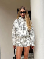Woman wearing a polka dot outfit standing against a white column.