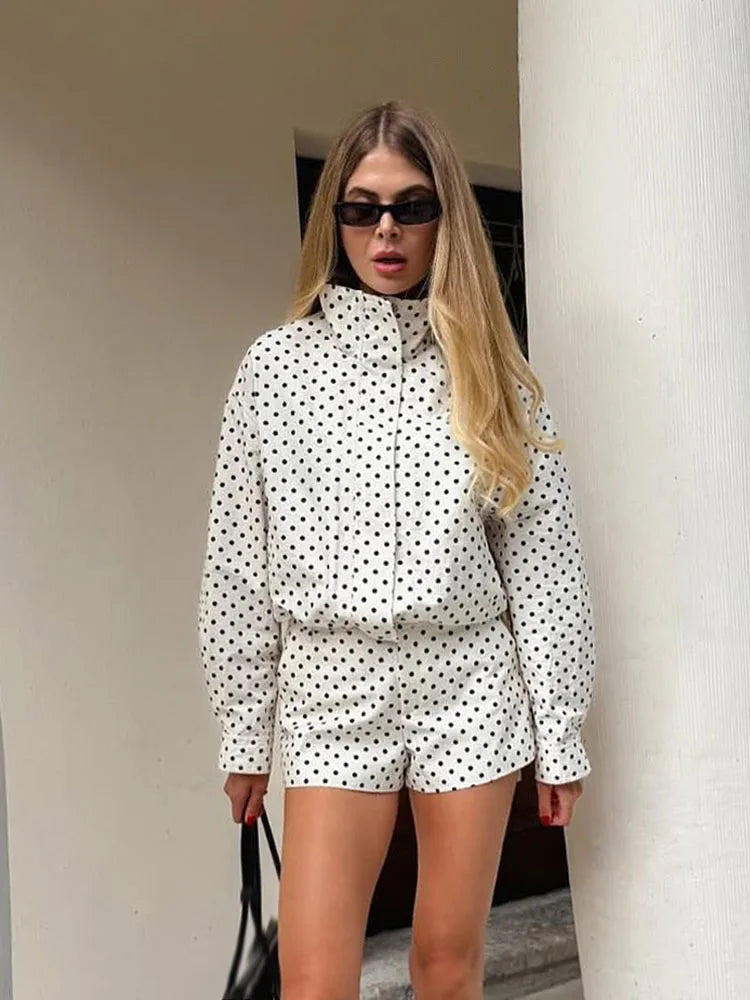 Woman wearing a polka dot outfit standing against a white column.