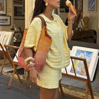 Woman in a yellow outfit holding a cone-shaped object in an art gallery.