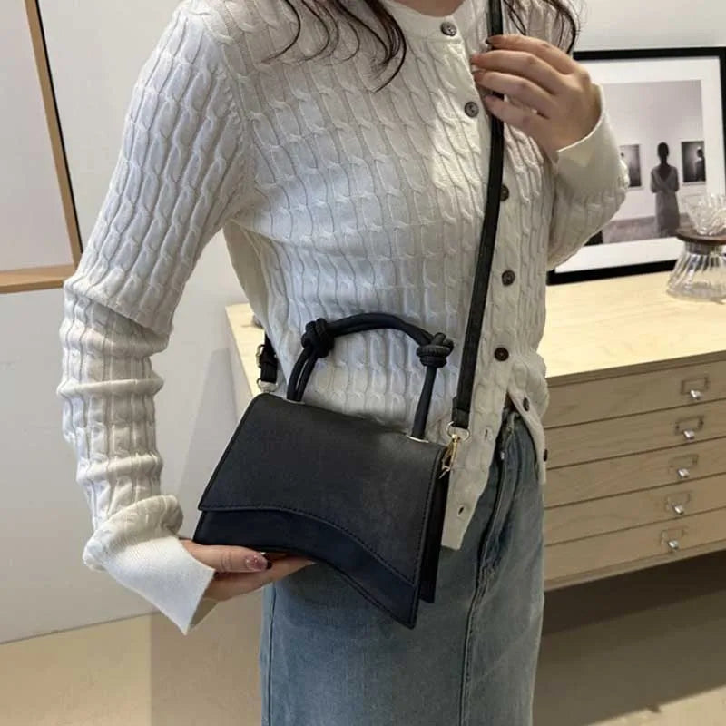 Person holding a black handbag in an indoor setting