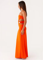 Woman wearing an orange strapless dress with cut-out design on a white background