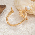 Gold bracelet with a pearl on a textured beige surface