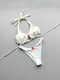 White bikini set with red bows on a gray background