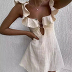 Beige and white dress with ruffled straps against a textured white background.