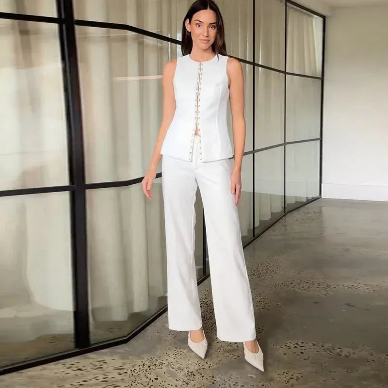 Woman in white sleeveless top and pants in a modern room.