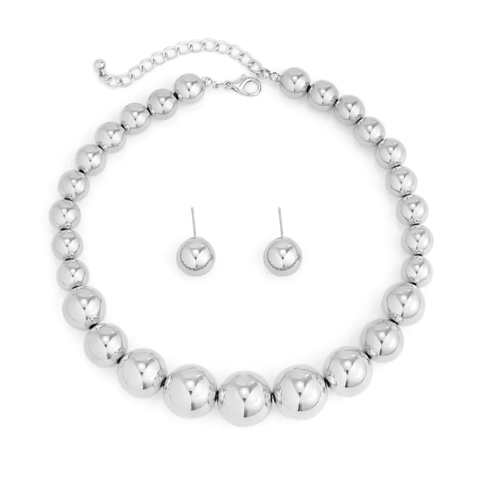 Silver beaded necklace and earrings set on a white background