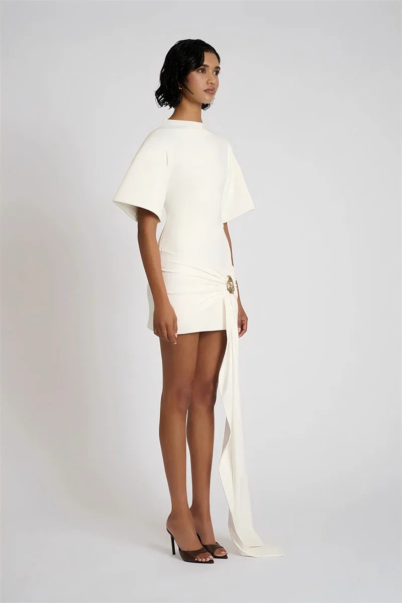Woman wearing a white dress with a slit on a plain background