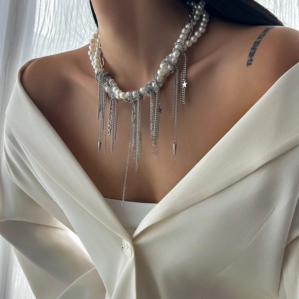 Pearl necklace with silver fringe on a person wearing a white blouse.