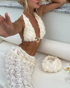 Woman in a white floral bikini sitting on a white couch with a decorative wreath.