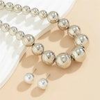 Silver beaded bracelet and earrings on a beige surface