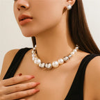 Woman wearing a pearl necklace and earrings against a neutral background