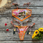 Colorful bikini set on a wooden surface with flowers and a straw hat.