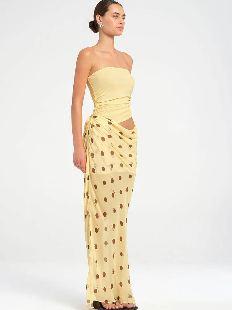 Woman wearing a yellow strapless dress with a polka dot pattern on a white background