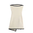 A white strapless mini dress with a solid backless design above knee, featuring a black belt.