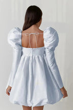 Light blue dress with puff sleeves and open back on a plain background