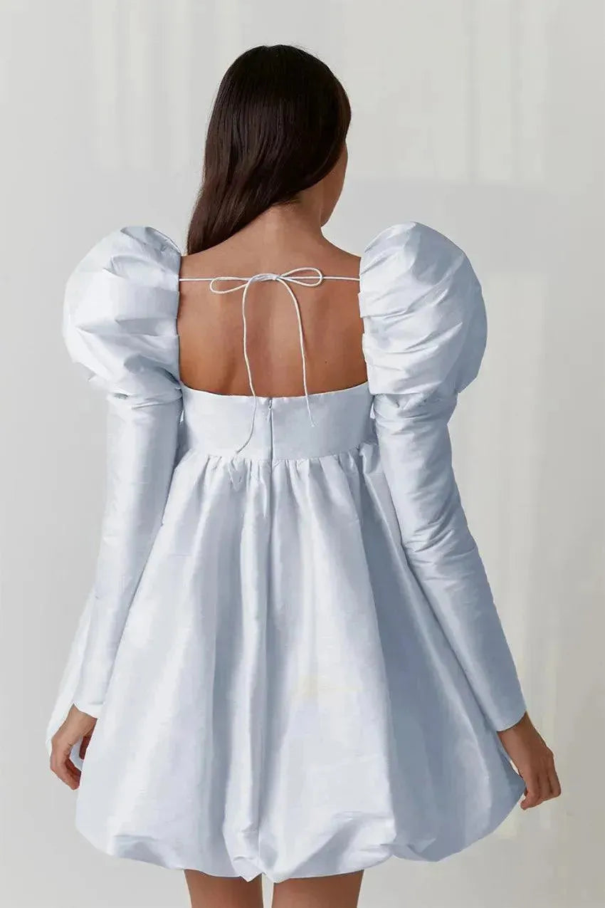 Light blue dress with puff sleeves and open back on a plain background