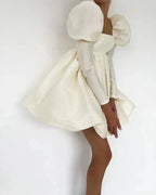 White dress with puffed sleeves and a fitted silhouette on a plain background.
