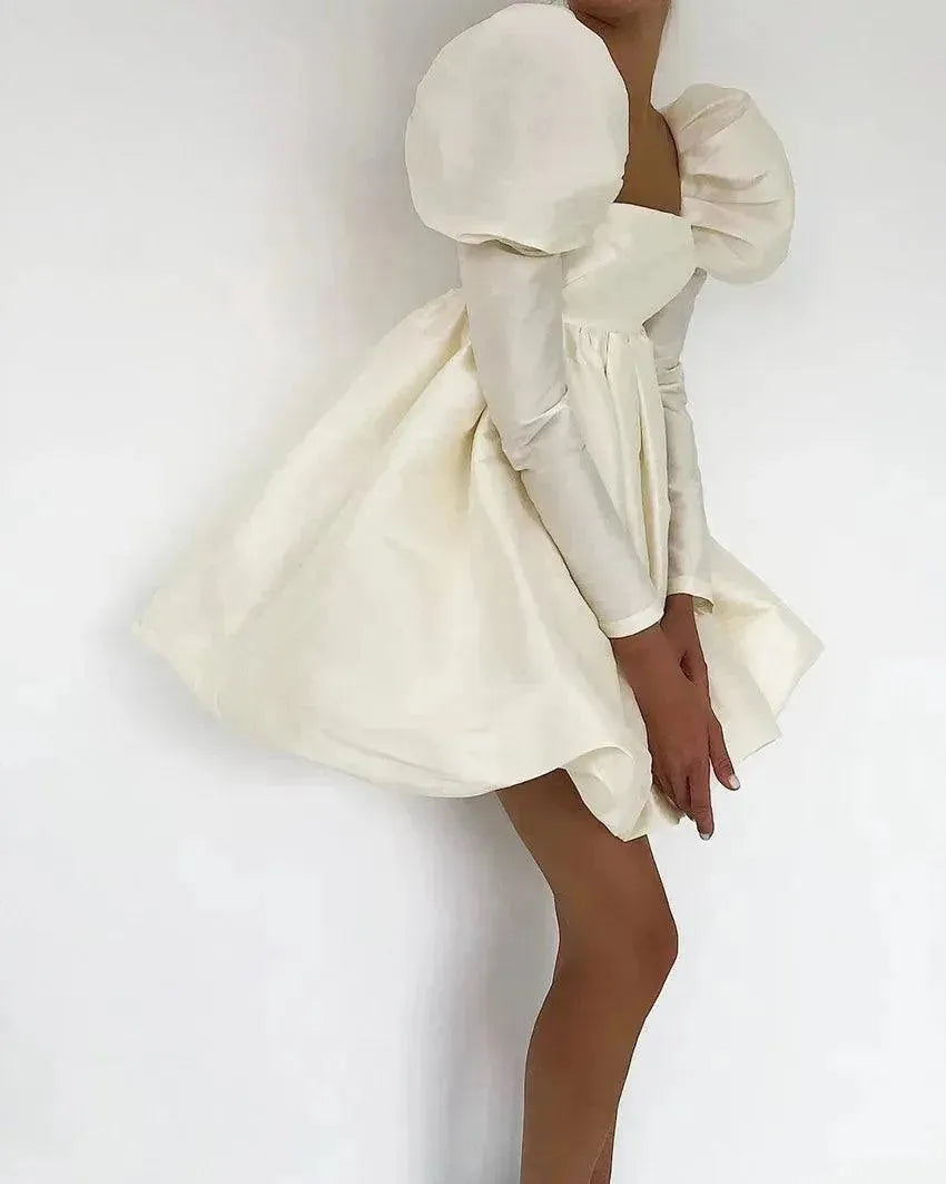 White dress with puffed sleeves and a fitted silhouette on a plain background.