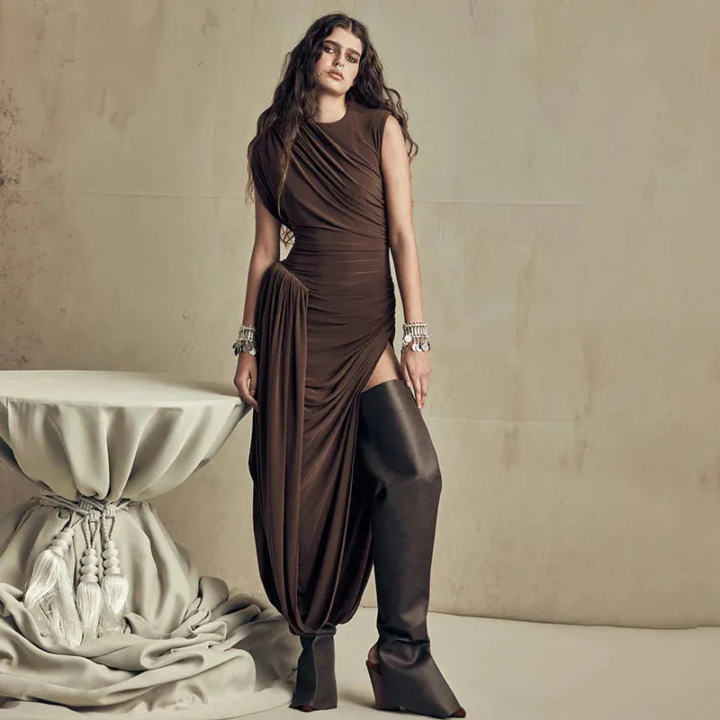 A person wearing a brown midi dress with a ruched waist, high neck, and no sleeves. The dress is floor-length.