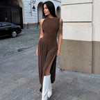 A person wearing a brown midi dress with a ruched waist and asymmetrical neckline, paired with white boots.