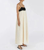 Person wearing a black top and long white skirt on a plain background