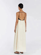 Woman wearing a long white dress with a black backless top on a white background