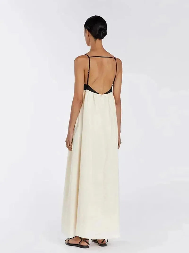 Woman wearing a long white dress with a black backless top on a white background