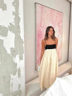 Woman in a white and black dress standing in a room with a pink abstract painting.