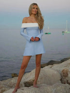 Woman in light blue dress standing on rocks by the sea