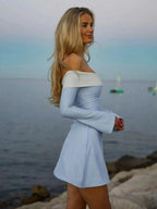 Woman in light blue dress standing by the sea