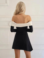 Woman wearing a black and white dress in a minimal white room.