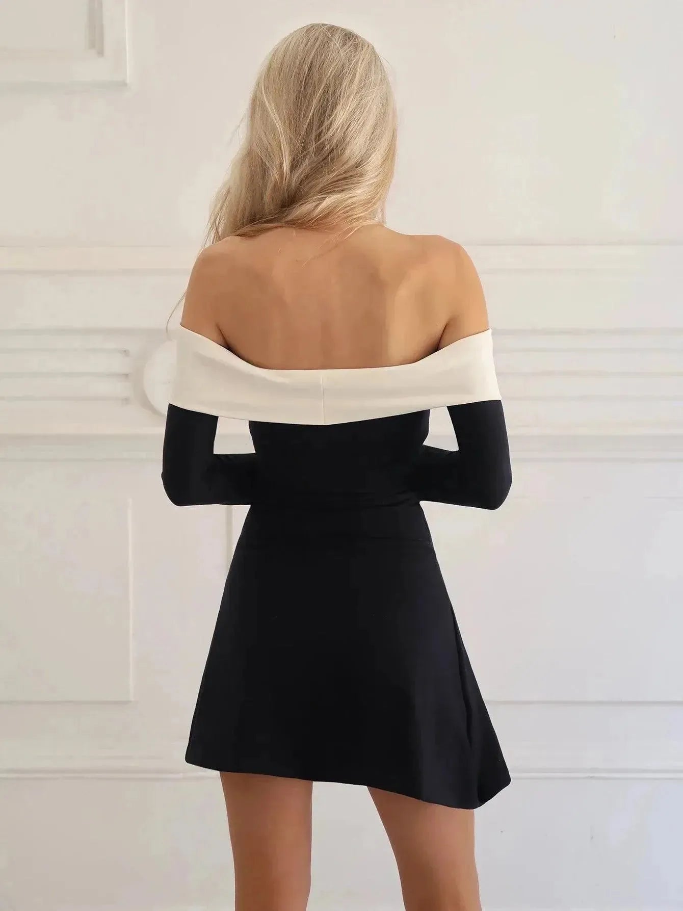 Woman wearing a black and white dress in a minimal white room.