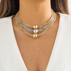 A woman wearing a multi-layered necklace with gold and silver balls.