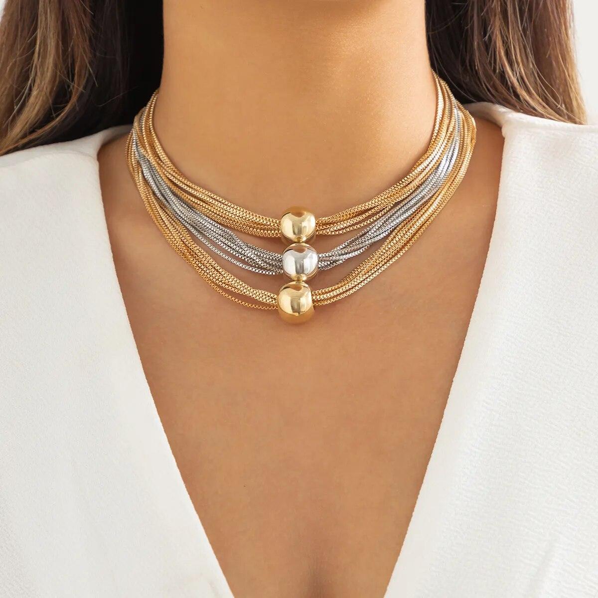 A woman wearing a multi-layered necklace with gold and silver balls.