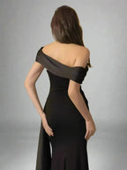 Woman wearing a black evening gown against a gray background