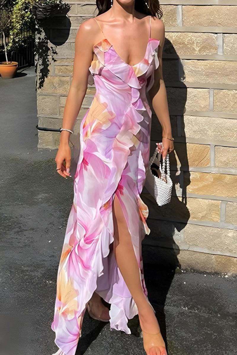 A woman wearing a floral print midi dress with spaghetti straps and a V-neck top, standing in a sunny location with brick walls in the background.