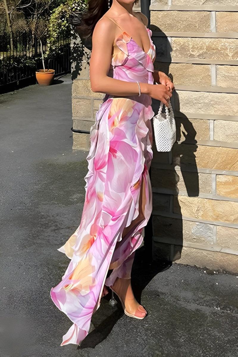 A woman wearing a floral print midi dress with spaghetti straps and a V-neck top, standing in a sunny location with brick walls in the background.