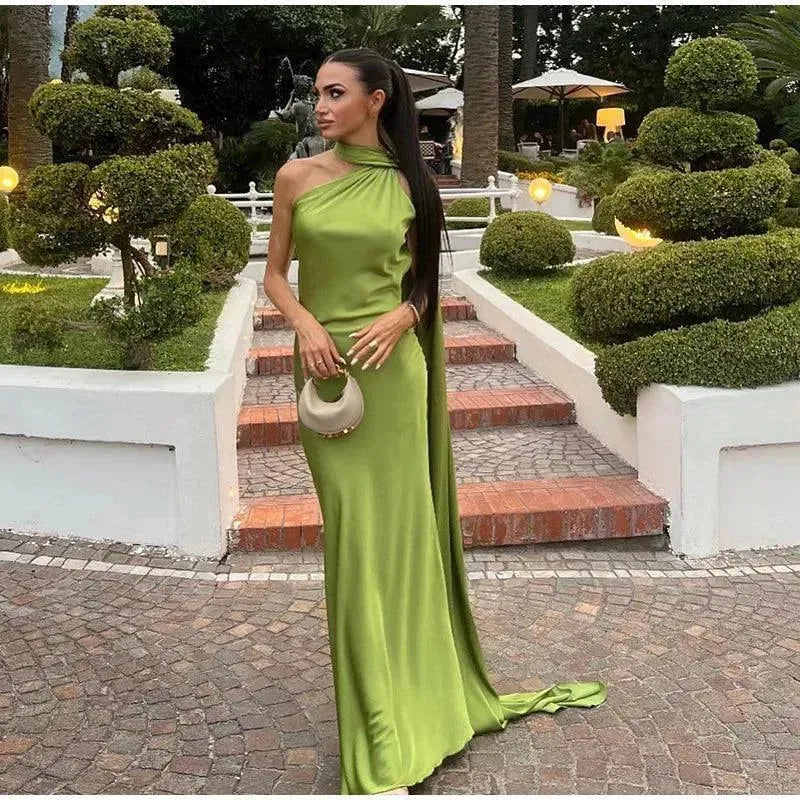 Woman in a green dress standing on a stone path with garden decorations.