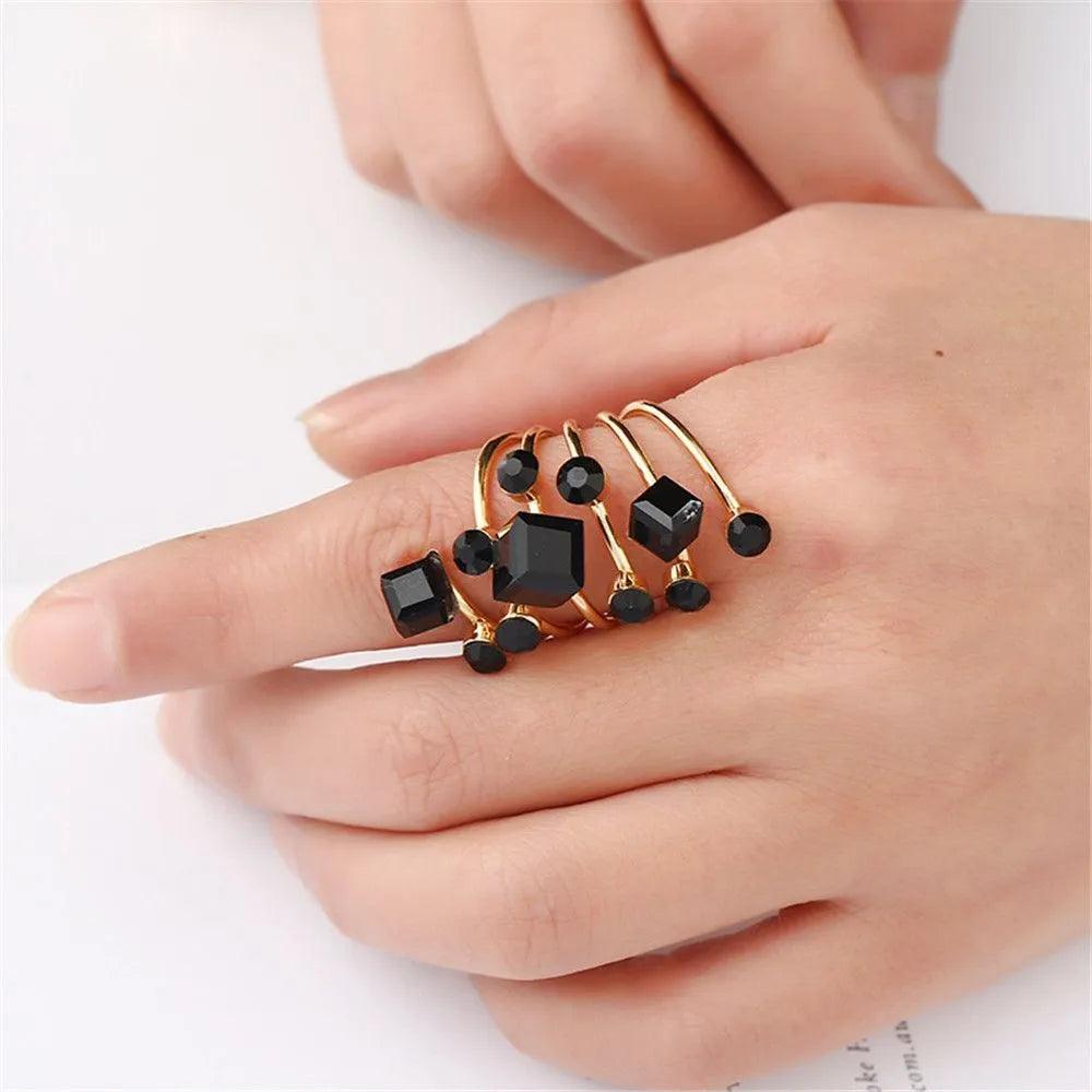 A hand wearing an oversized copper ring with multiple black crystals and rhinestones.